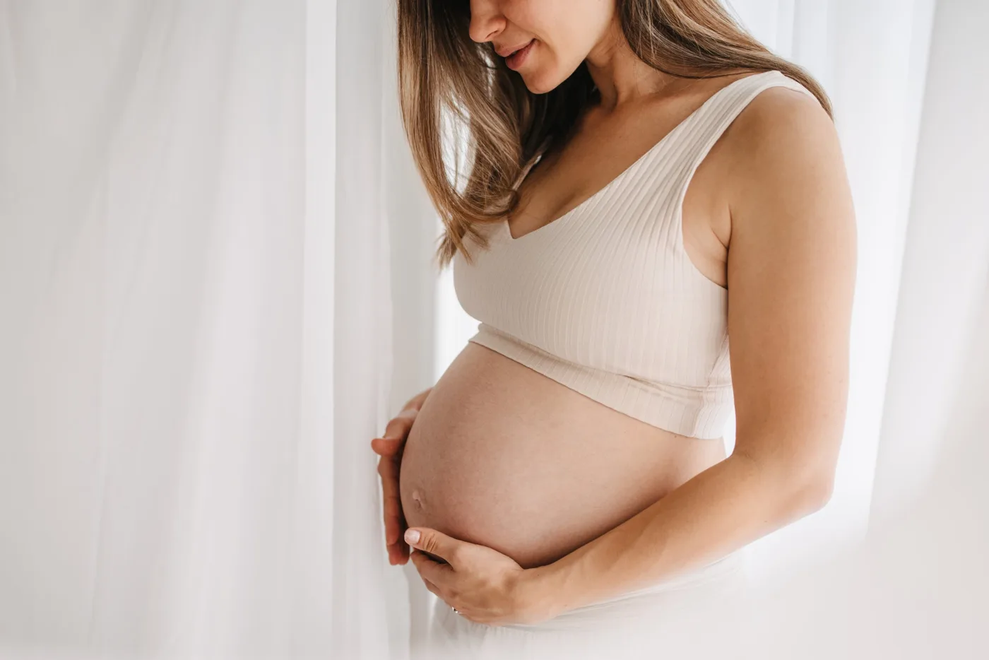 Gravid kvinne som holder hendene rundt magen