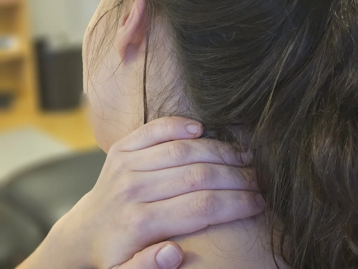 Kvinne som holder seg på nakken der det gjør vondt